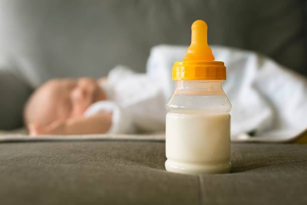 eine flasche milch und ein schlafendes baby. formel milchfütterung und schlafplan für säuglinge. - color image food dairy product people stock-fotos und bilder
