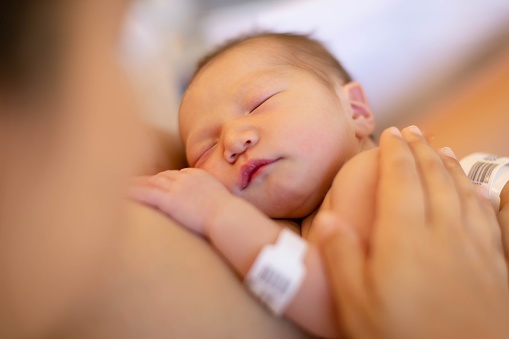 Una madre sosteniendo a su bebé recién nacido en su pecho, teniendo piel sobre piel. Parto en el hospital. photo