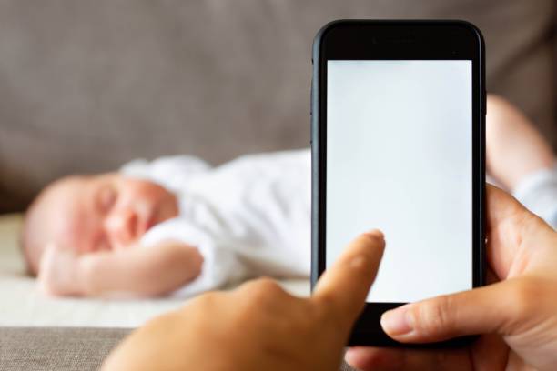 istock A mother on her phone next to her sleeping baby. 1356026403