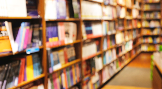 Blur background of book shelf store decorated with wood and warm light