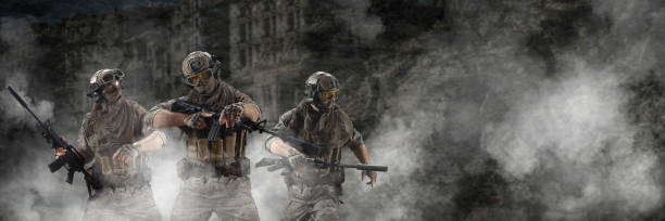 Three mercenary soldiers during a special operation in the smoke against the background of a ruins - photo with copy space. Format photo 3x1 stock photo