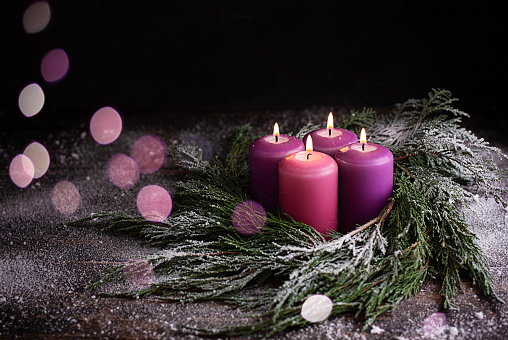 Christmas eve, wreath with four burning purple advent candles.