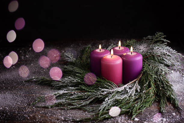 Christmas eve, wreath with four burning purple advent candles. Christmas eve, wreath with four burning purple advent candles on a dark wooden snowy background with festive bokeh lights. advent photos stock pictures, royalty-free photos & images