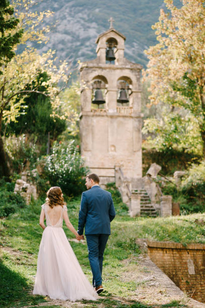 istock Bride and groom walk through the park to the old chapel. Back view 1356032885