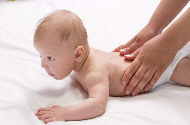 masaje para bebés, manos de primer plano en la espalda del bebé - acostado boca abajo fotografías e imágenes de stock