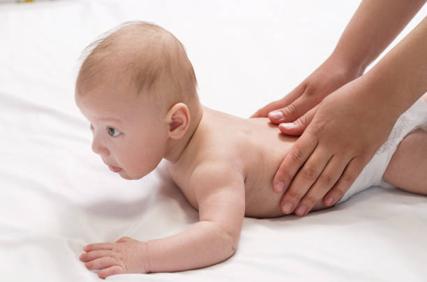 massage bébé, mains rapprochées sur le dos de bébé - être étendu sur le ventre photos et images de collection
