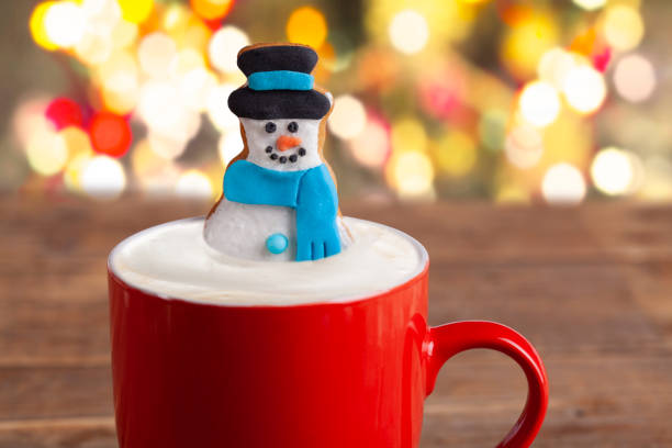 Christmas gingerbread snowman in hot chocolate on rustic wooden table