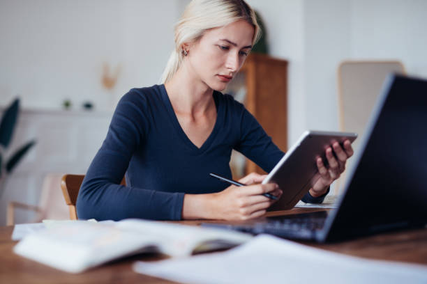 istock Female student at home studying at table with tablet 1356036282