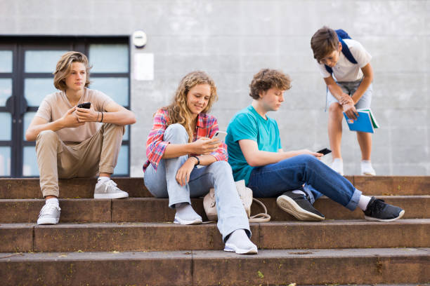 istock Teens with smartphones on stairs beside shool building 1356042589