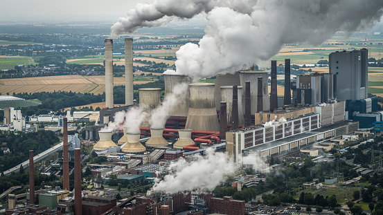 Aerial view of a lignite burning power station in North Rhine Westphalia - Germany. Chimneys and cooling towers releasing smoke and steam into the atmosphere. The power plant is also releasing CO2 which contributes to global warming and climate change.