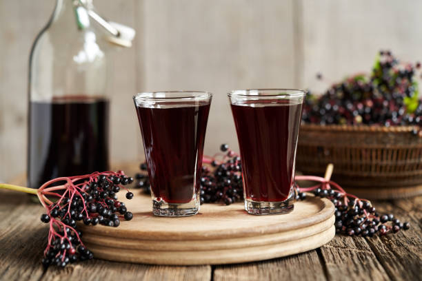 Two glasses of black elder syrup with fresh  elderberries Two glasses of black elder syrup with fresh Sambucus berries sambucus nigra stock pictures, royalty-free photos & images