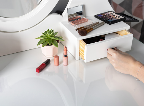 woman opens a drawer of white dressing table with products for make-up. Make-up accessories in the workplace artist