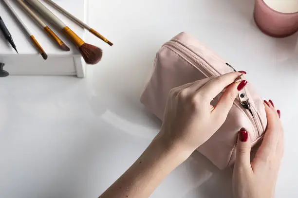 Photo of female hands open  pink cosmetic bag for making makeup. Concept for storage and handling of cosmetic products