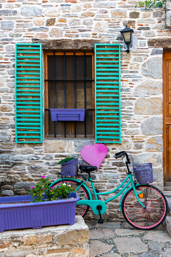 Green vintage bike with basket full at flowers next to an old building in Old Datca