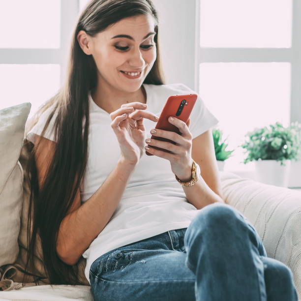 istock young woman with a smartphone sitting on a comfortable sofa 1356054832