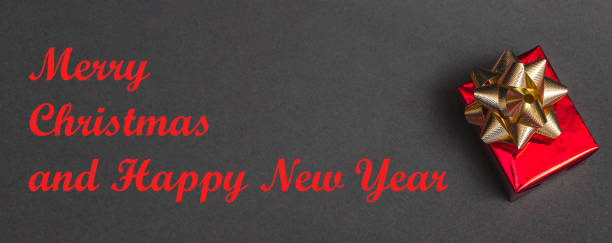 istock Beautiful gift red box with a gold bow on a black background close up, top view, with copy space 1356055766