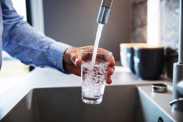 Man Pouring Himself Water Mature male hand  pouring a glass of water from tap in the kitchen sink water photos stock pictures, royalty-free photos & images