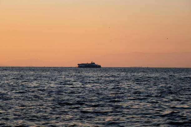 a ship on the horizon Look at the point where blue and orange meet at sunset in Izmir, you can always see a ferry there. kompozisyon stock pictures, royalty-free photos & images