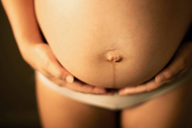 a pregnant woman holding her stomach. prenatal symptoms and health. - bumpy imagens e fotografias de stock