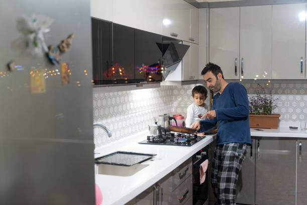 le père cuisine de la nourriture pour son fils sur la cuisinière - gas counter photos et images de collection