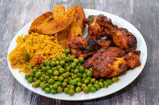 Peri-Peri chicken wings meal with spicy wedges, peas and rice