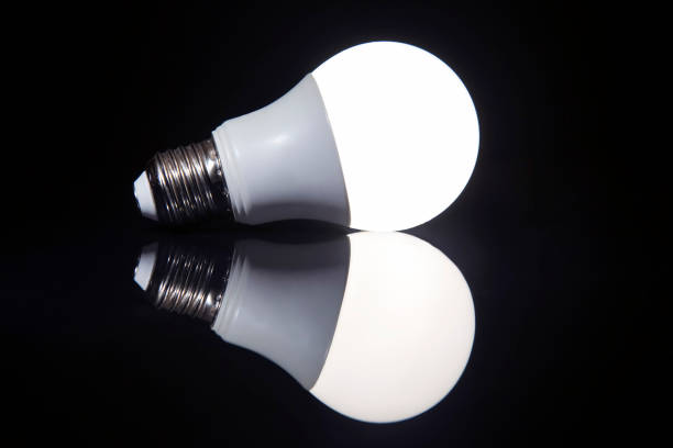 istock LED lamp is on against a dark background with surface reflection. savings on electricity. electrical industry 1356067781