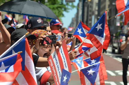Spectators hold Puerto Rican flag and cheer on the marchers as the Puerto Rican Day Parade proceeds up Sixth Avenue in New York City on June 9, 2019.