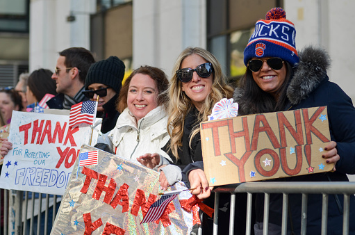 Spectators hold the United States flag and cheer on the marchers as the Veteran's Day Parade proceeds up Sixth Avenue in New York City on November 11, 2018.