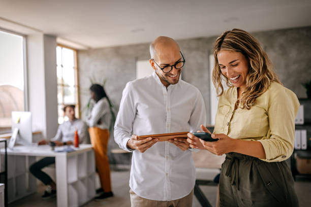 businessman and businesswoman smiling looking at phone - working bildbanksfoton och bilder