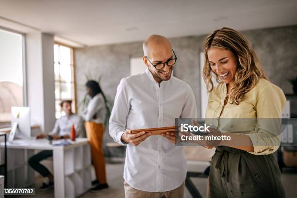 Businessman And Businesswoman Smiling Looking At Phone Stok Fotoğraflar & Ofis‘nin Daha Fazla Resimleri
