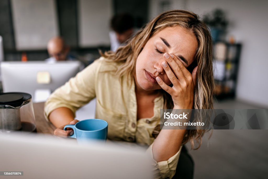Tired business woman rubbing eyes Tired and exhausted young female entrepreneur drinking coffee and rubbing eyes while feeling stressed and worried in coworking space Women Stock Photo