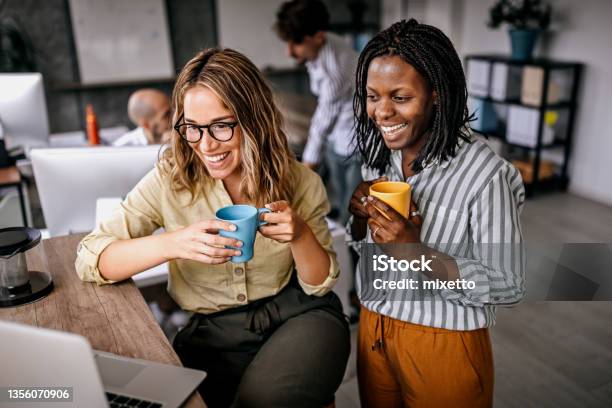 Female Coworkers Looking At Laptop And Laughing Stock Photo - Download Image Now - Employee, Office, Happiness