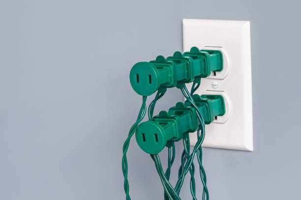 Electrical outlet overloaded with Christmas string lights. Holiday decoration safety, hazards and fire prevention concept. stock photo