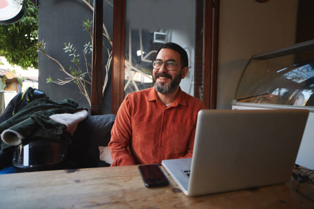 istock A man is talking to his friends while working at the table with his computer in a cafe outside in winter 1356073890