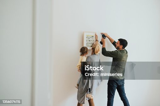 istock Family Hanging a Painting on the Wall 1356074115