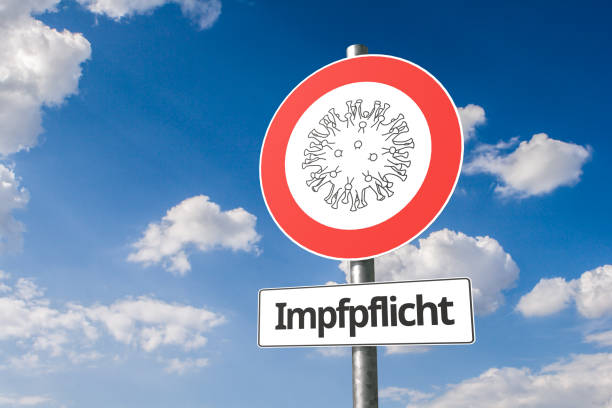 Vaccine mandate in German speaking countries concept: Corona virus - Schematic image of a virus on a no entry road sign with the German text "Impfpflicht" ("Vaccine Mandate") below. Vaccine mandate in German speaking countries concept: Corona virus - Schematic image of a virus on a no entry road sign with the German text "Impfpflicht" ("Vaccine Mandate") below. mandate photos stock pictures, royalty-free photos & images