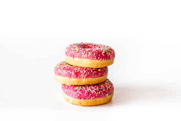 istock Sweet snacks - pink frosted donuts with colorful sprinkles 1356078128
