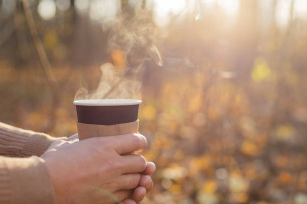 istock A man holds a disposable paper cup with a drink in the park in the fall. 1356078507