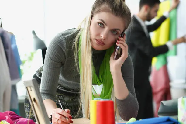 Photo of Blonde creative woman take order on phone for new clothes from client