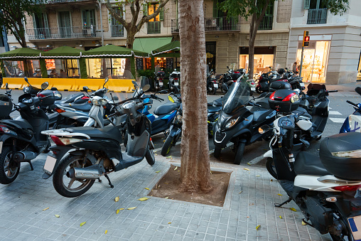 Many modern metal motorcycles parked on asphalt roadside in city at daytime in summer