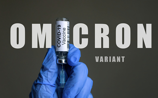 Póster de la variante COVID-19 de Omicron, frasco de vacuna y jeringa en manos del médico photo