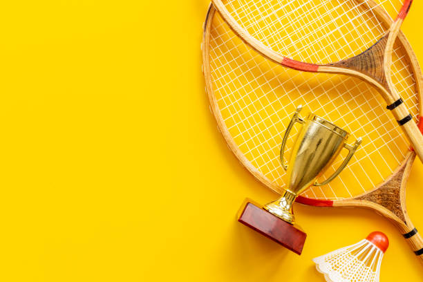 istock Small golden trophy cup with rackets and shuttlecock for winner, top view 1356085396