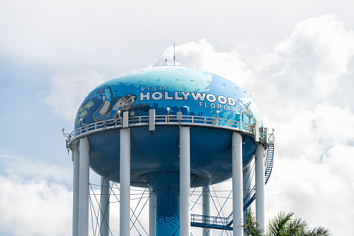 Hollywood, USA - July 8, 2021: Florida city town in Broward County with water tower sign entrance on sunny day in North Miami Beach area isolated against sky