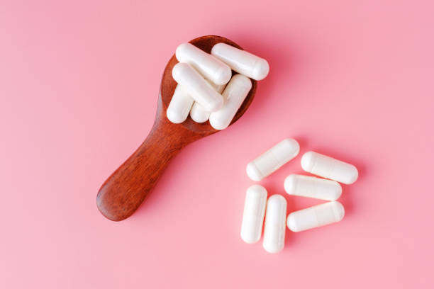 istock Collagen capsules in tea spoon on pink background, top view. 1356094338