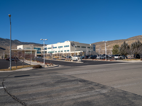 Carson City, Nevada USA - November 28, 2021: Street view of the Carson Tahoe Regional Medical Center with cars and trucks in the parking lot against a blue sky.
