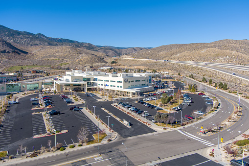 Carson City, Nevada USA - November 28, 2021: Aerial view of the Carson Tahoe Regional Medical Center with cars and trucks in the parking lot against a blue sky.