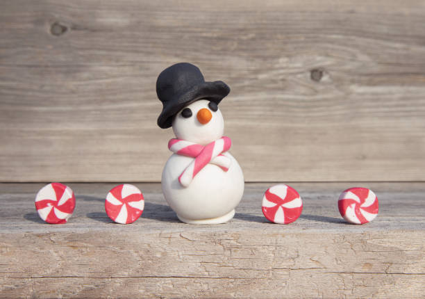 Miniature snowman with candies in front of soft wood background. Playful Christmas concept. Handmade with clay. polymer clay sweets stock pictures, royalty-free photos & images