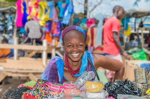 Dakar, Senegal, Africa – October 10, 2021: Unidentified market vendor welcoming tourists in front of her plastic jewelry stall, Sandaga Market
