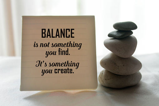 Life balance inspirational quote on notepaper - Balance is not something you find. It is something you create. With balancing stone and notes reminder on white table indoor decoration background.