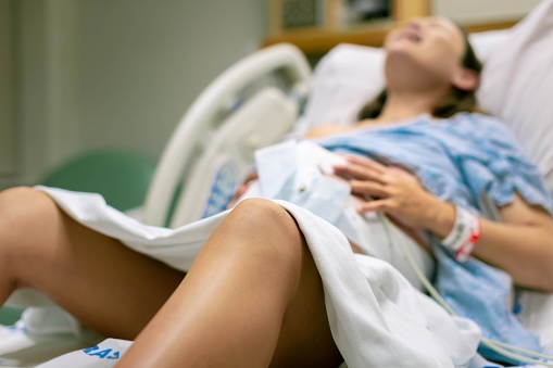 Una mujer en trabajo de parto, con contracciones dolorosas, acostada en la cama del hospital. Parto y parto del bebé. photo